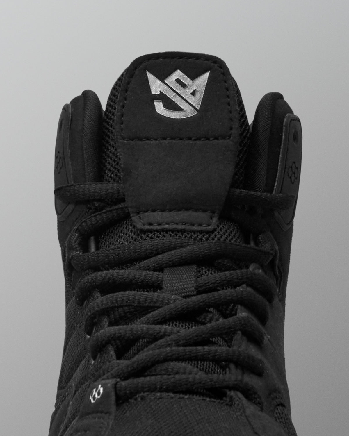 Black Jordan Burroughs wrestling shoes with a brand logo on a gray background
