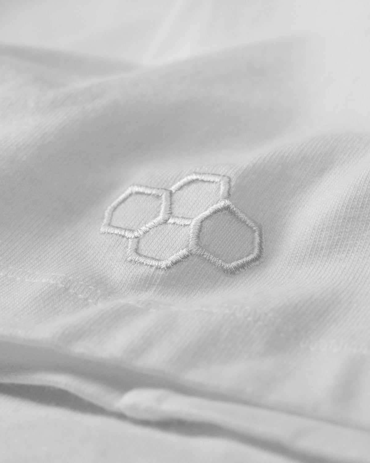 Close-up of a white fabric with an embroidered hexagonal pattern.