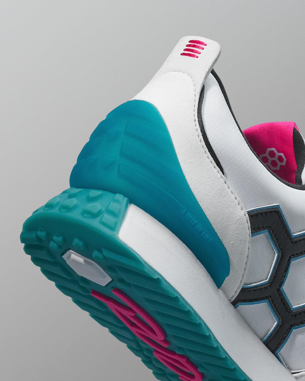 Close-up of a sneaker with teal sole and pink accents on a gray background