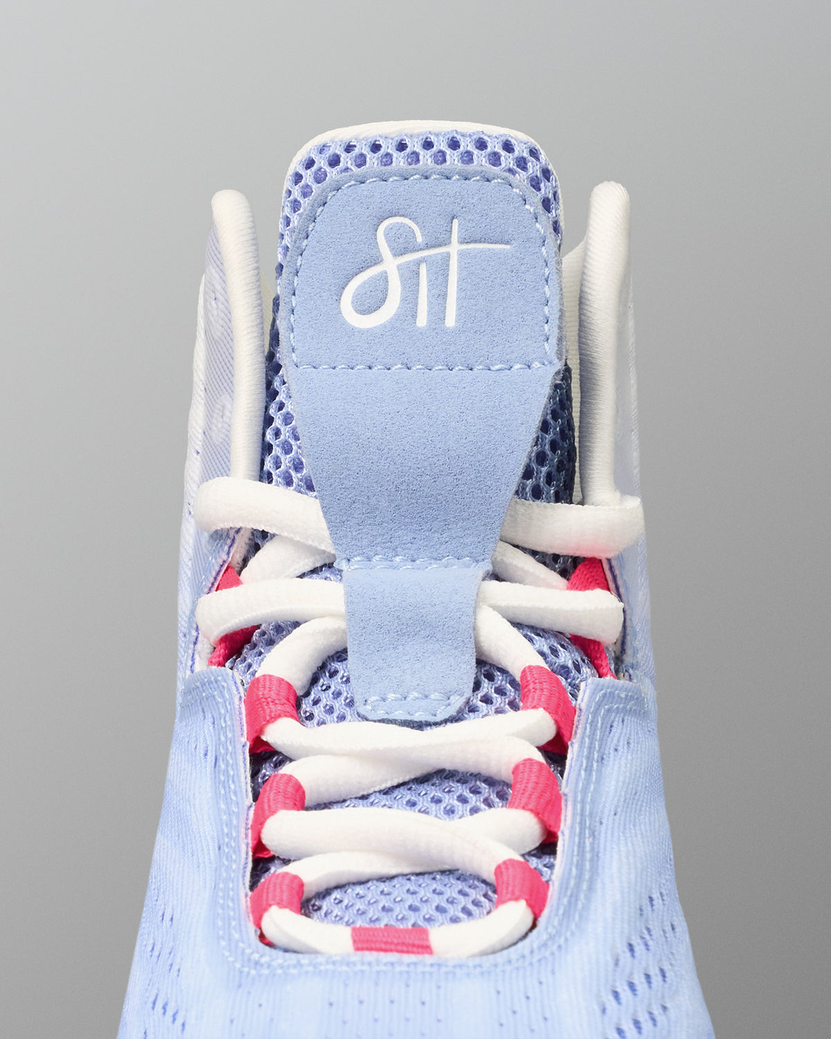 Light blue wrestling shoe with white and pink laces on a gray background