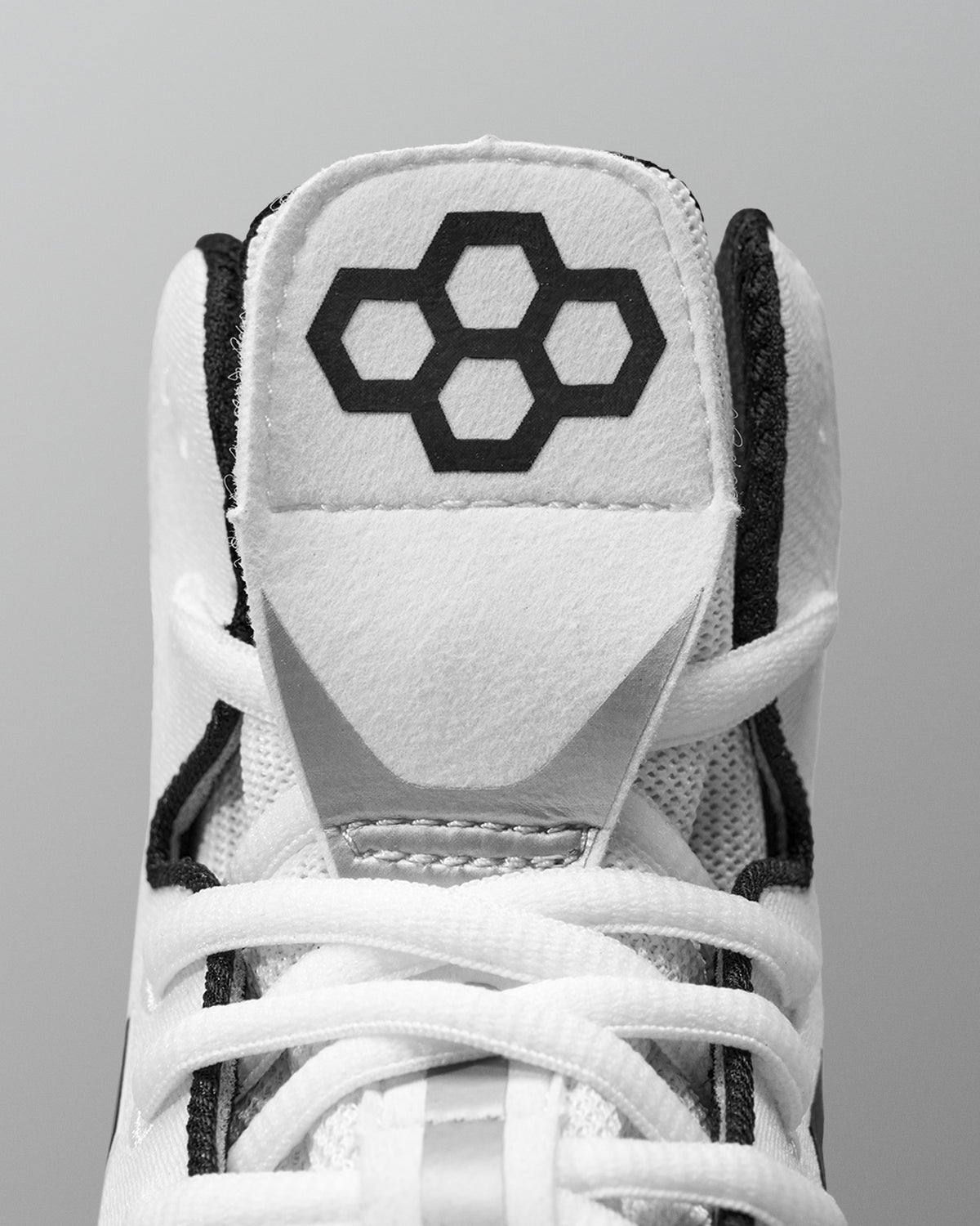White Wrestling shoe with black hexagonal logo on a gray background