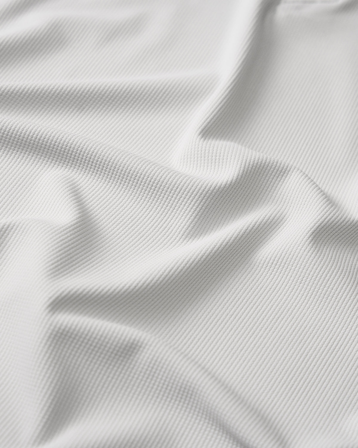 Close-up detail of the RUDIS Go-To Polo in Lunar Gray, highlighting the finely ribbed, textured fabric with subtle vertical lines and natural folds that showcase the material's surface and construction.