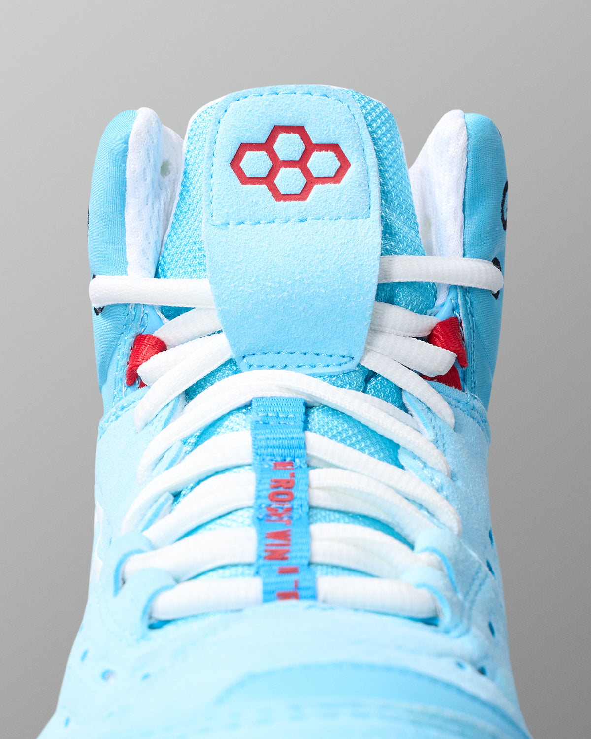 Light blue wrestling shoe with white laces and red accents on a gray background