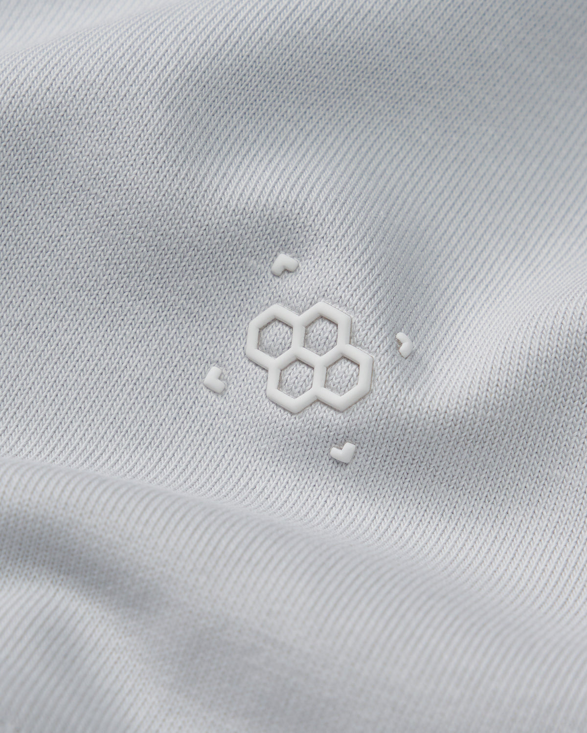 Close-up of a white fabric with a subtle logo on a light gray background