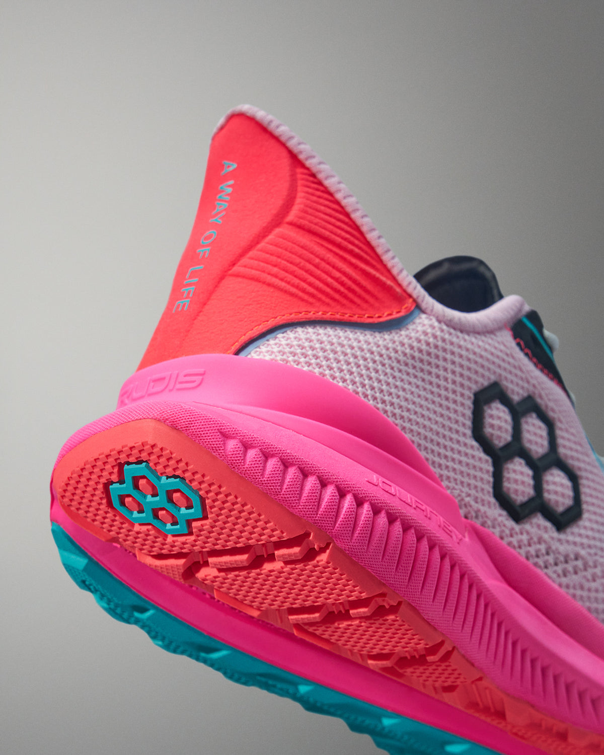 Close-up of a pink and red athletic shoe with brand logo on a gray background
