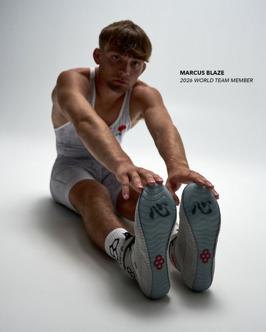 Wrestler, Marcus Blaze, stretching in RUDIS Samurai Speed Youth Wrestling Shoes in Kokoro, showcasing the translucent blue outsoles with red RUDIS emblems and gray high-top design.