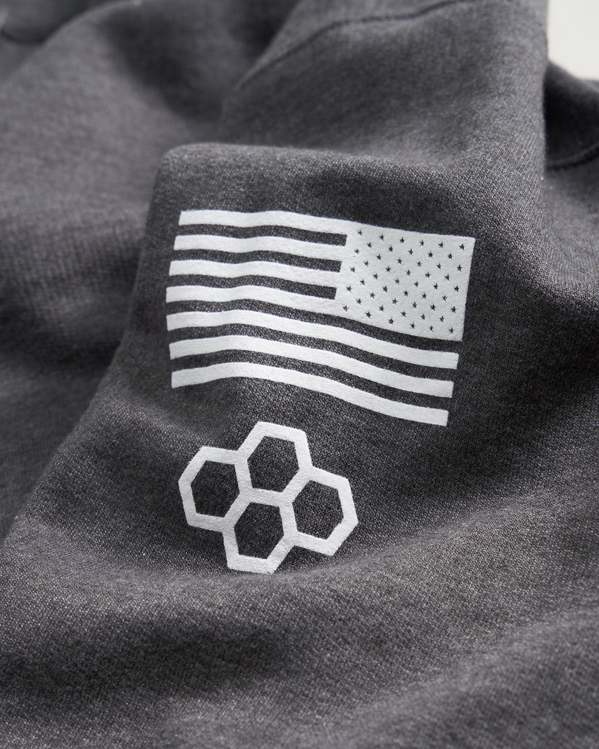 A close-up view of a dark gray fabric featuring a white American flag design and a geometric honeycomb pattern