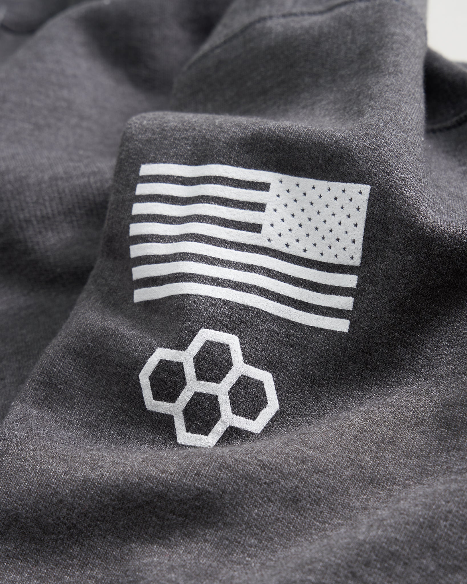 A close-up view of a dark gray fabric featuring a white American flag design and a geometric honeycomb pattern
