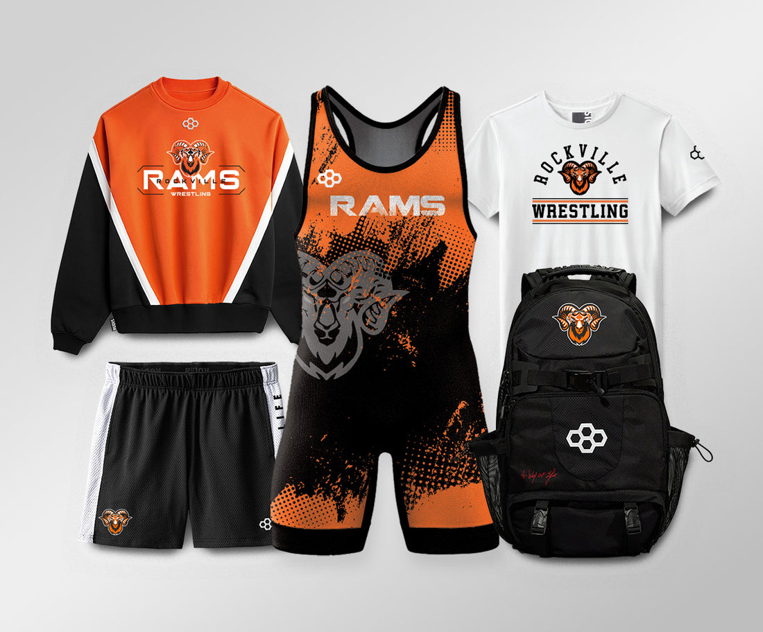 Collection of custom team uniform gear of Rams wrestling gear including a sweatshirt, singlet, shorts, and backpack on a light gray background.