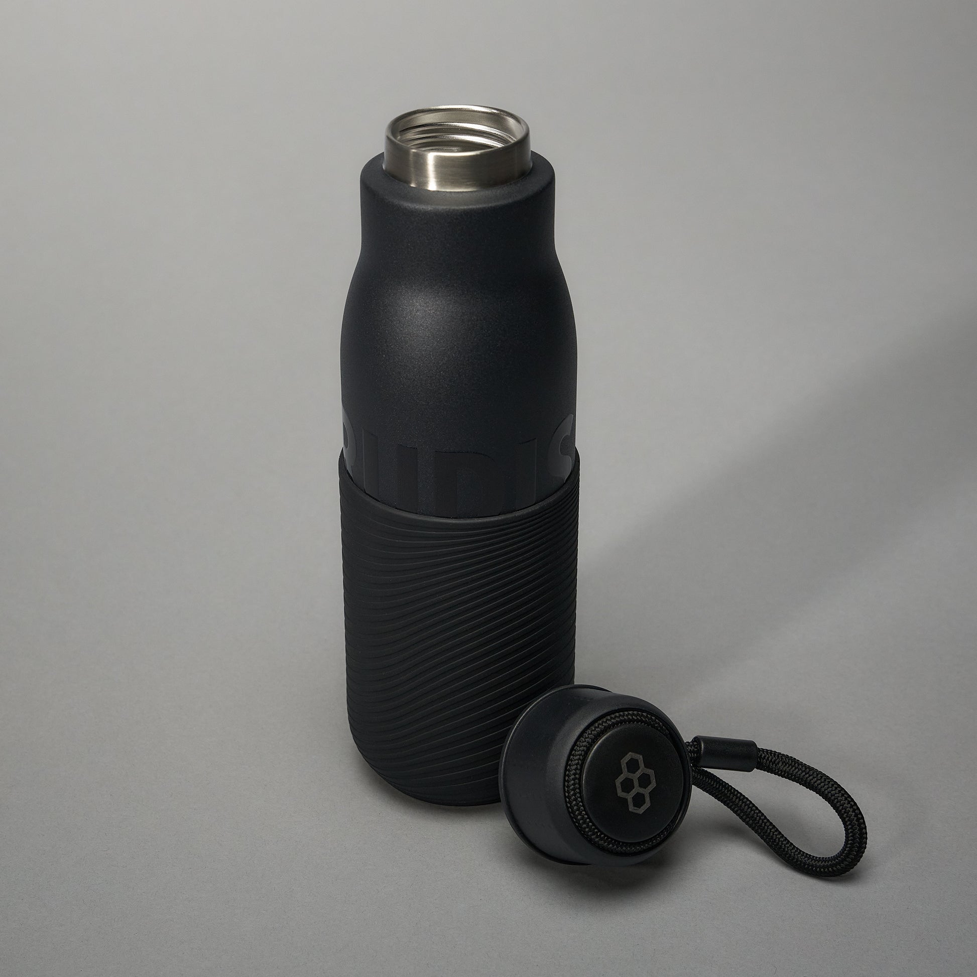 A sleek black insulated water bottle with a textured grip and a detachable lid designed for stylish hydration on the go