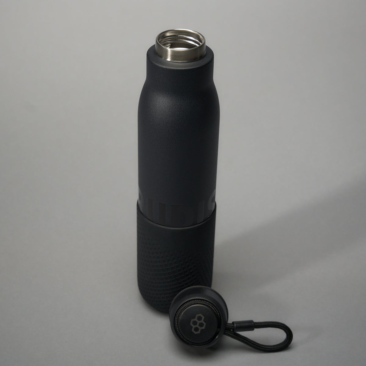 A sleek black insulated water bottle featuring a textured grip and a stainless steel opening accompanied by a detachable lid with a loop for easy carrying