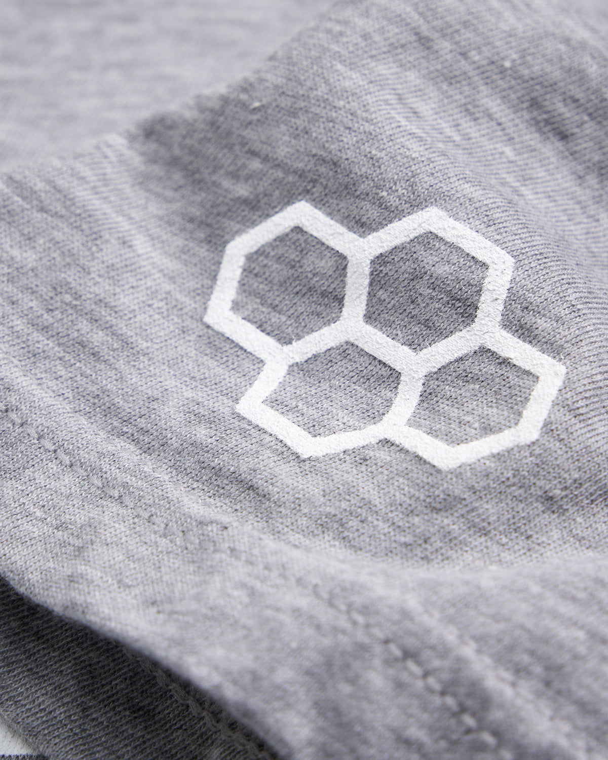 A close-up view of a light gray fabric featuring a white hexagonal logo highlighting the texture and detail of the material