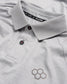 A detailed view of a light gray polo shirt featuring a stylish collar black buttons and a subtle honeycomb logo design