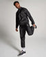 A man models a stylish black athletic tracksuit showcasing a modern design paired with signature footwear and accessories