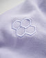 A close-up view of a soft lavender fabric featuring a stylized embroidered honeycomb design in light blue thread