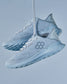 Light blue athletic shoes with a breathable mesh upper and a textured sole stylishly suspended against a soft blue background