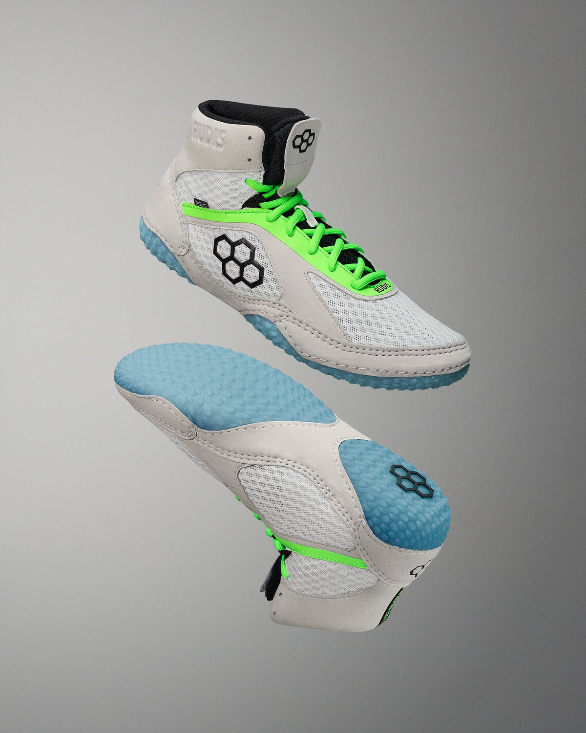 White wrestling shoes with green laces and blue soles on a gray background