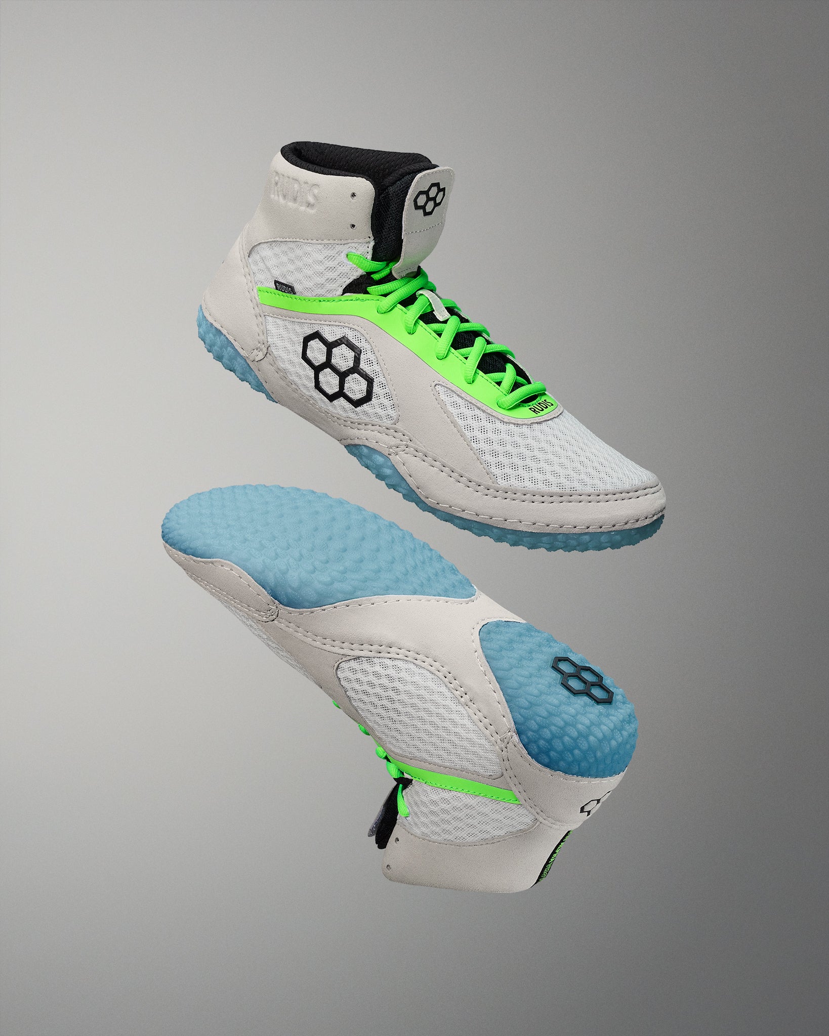 White wrestling shoes with green laces and blue soles on a gray background