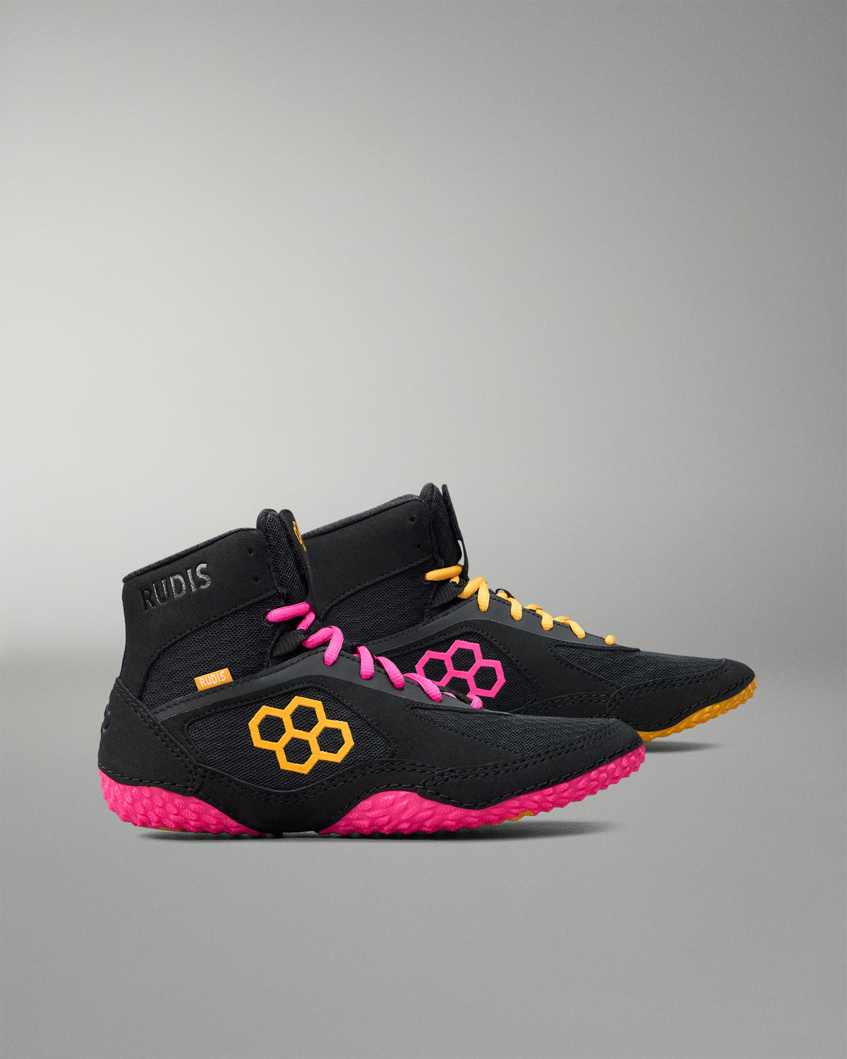 Black wrestling shoes with pink soles and yellow accents on a gray background