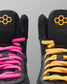 Black wrestling shoes with pink and yellow laces on a gray background