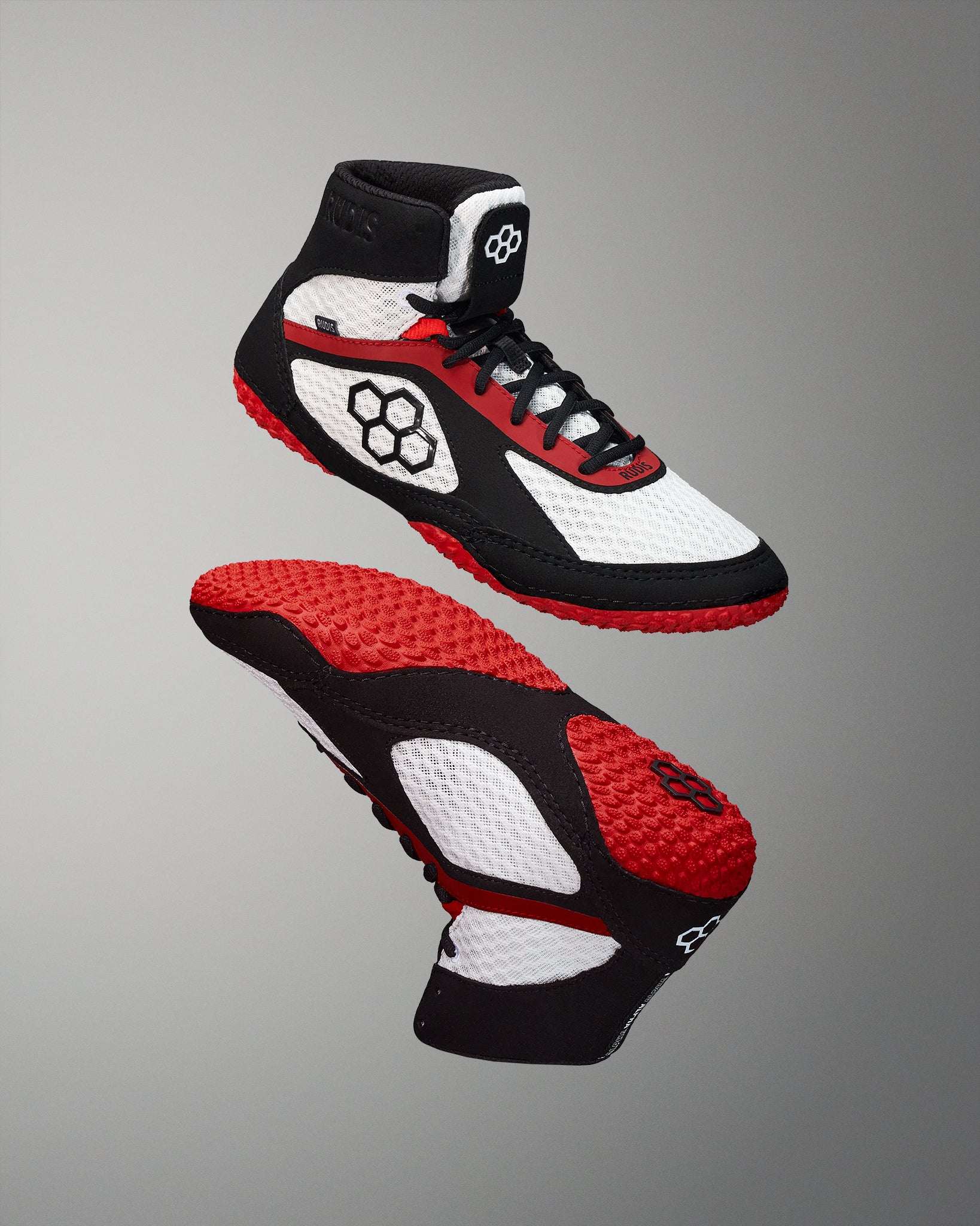 Wrestling shoe in white, black, and red, featuring a breathable mesh upper, padded collar, and textured red and black sole designed for grip.