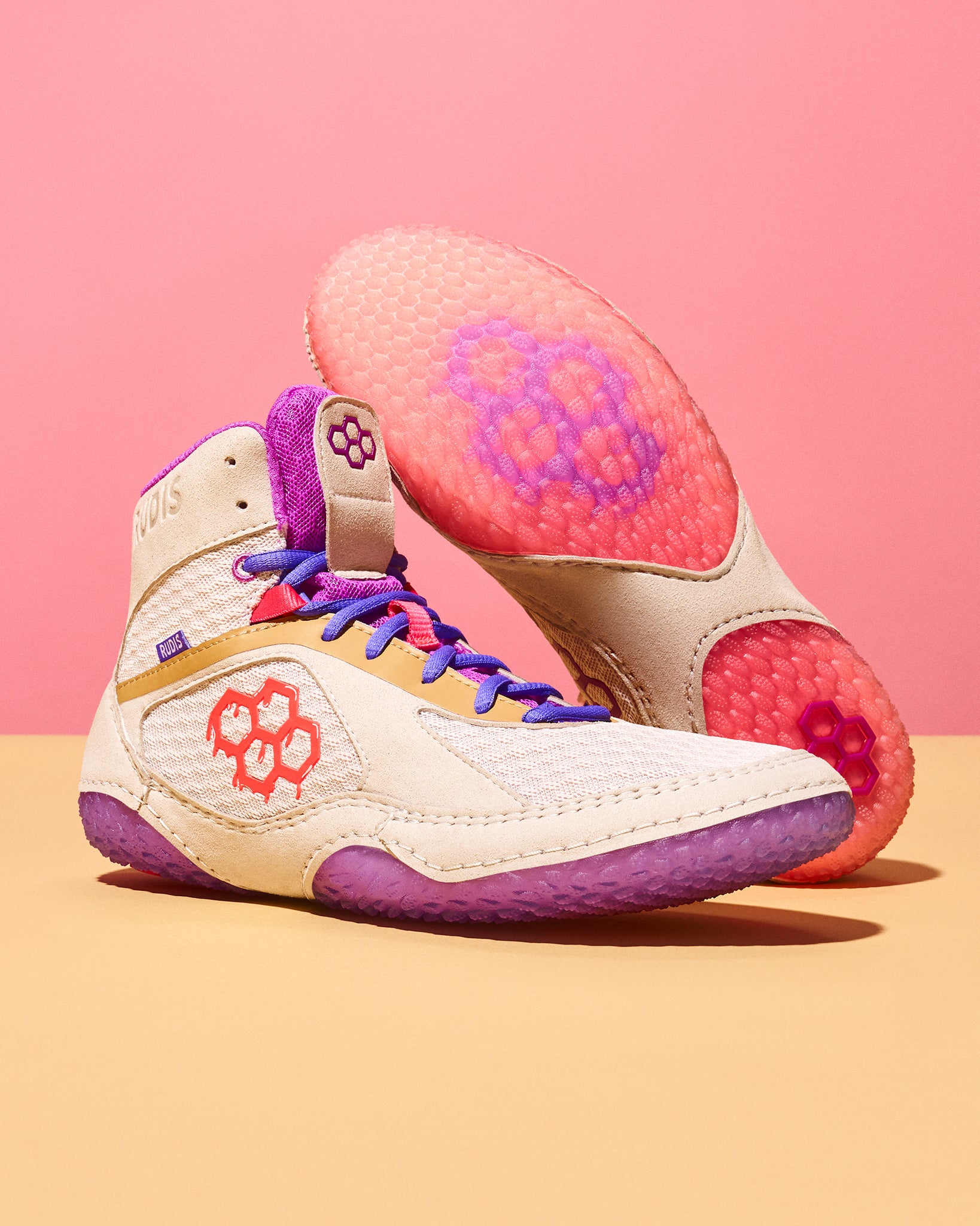 Pair of wrestling shoes with pink and purple accents on a pink background