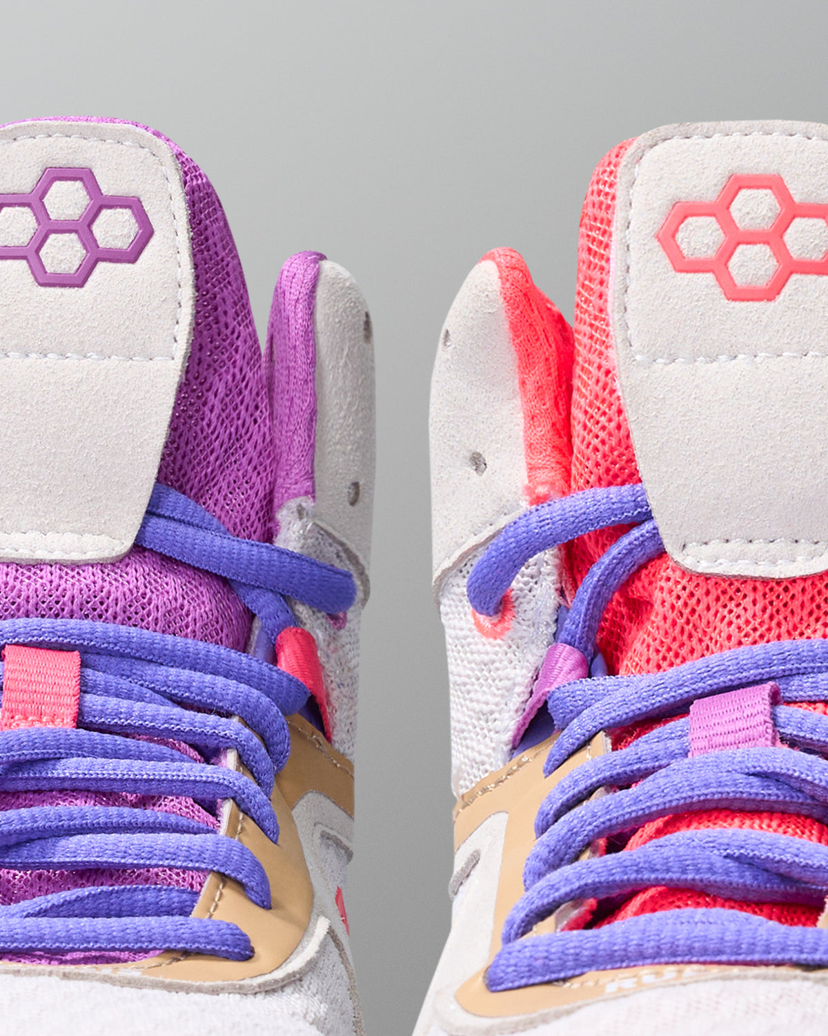 Pair of colorful wrestling shoes with purple, pink, and red accents on a gray background
