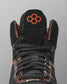 Black sneaker with orange logo on a gray background
