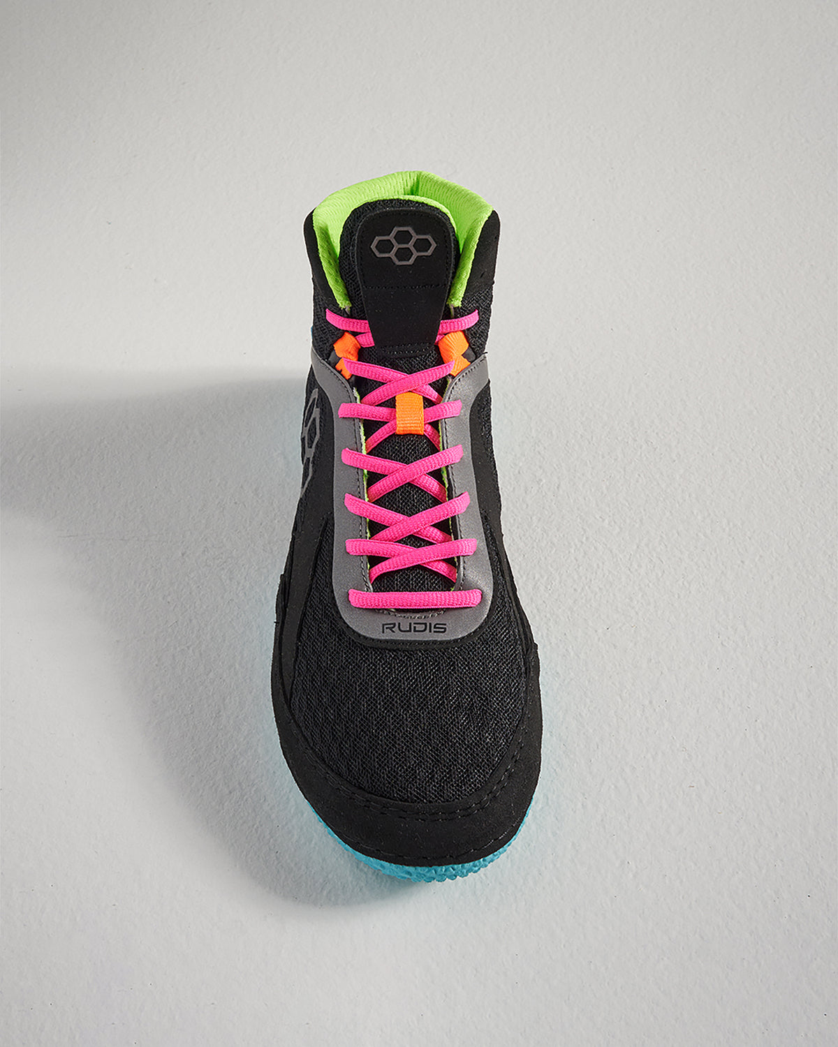 A top view of a modern black athletic shoe featuring bright pink and orange laces a green collar and a textured sole for traction