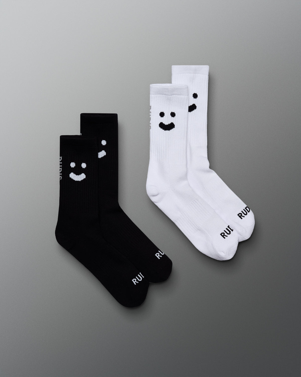 Two pairs of socks, one black and one white, with smiley face designs on a gray background.