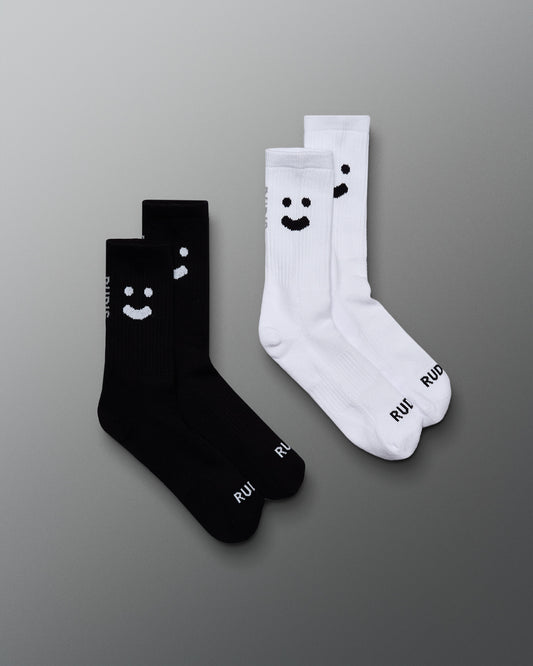 Two pairs of socks, one black and one white, with smiley face designs on a gray background.