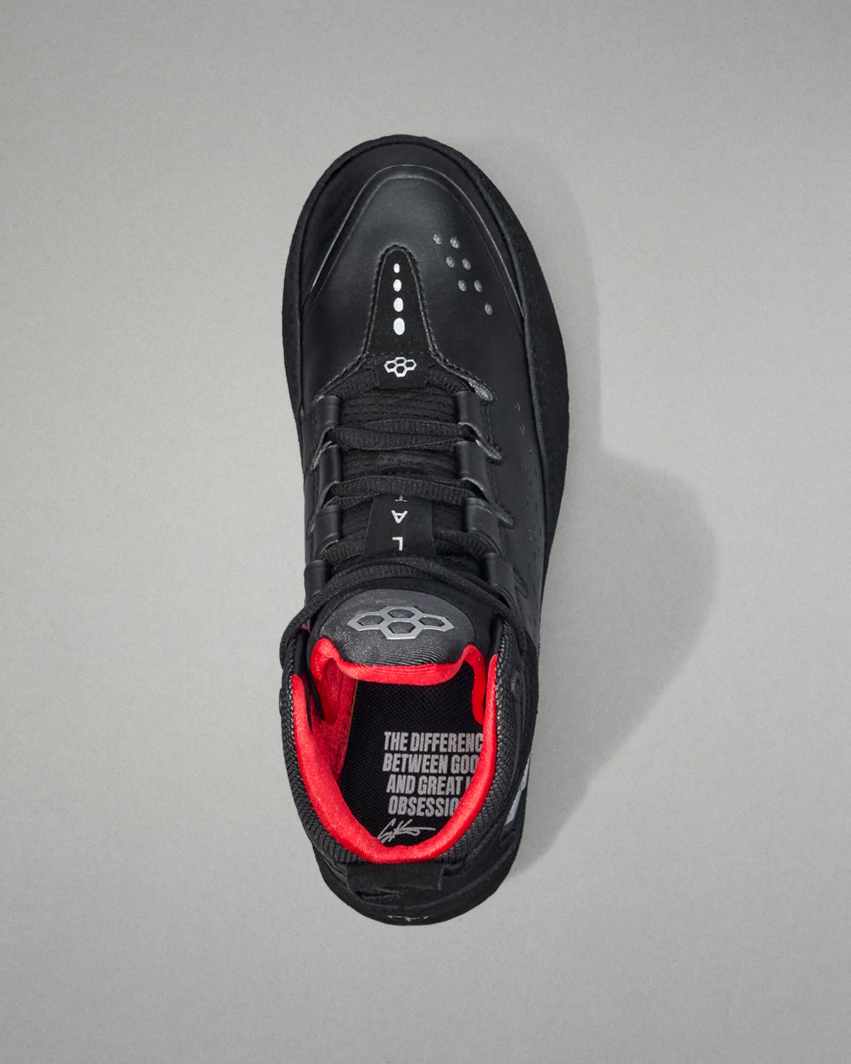 Black wrestling shoe with red interior on a gray background