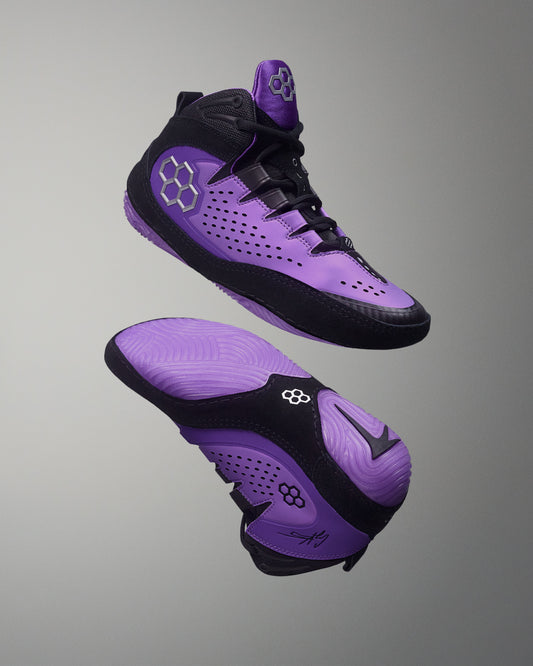 Purple and black wrestling shoes on a gray background