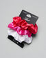Set of three satin scrunchies in red, pink, and white on a gray background with a brand label.