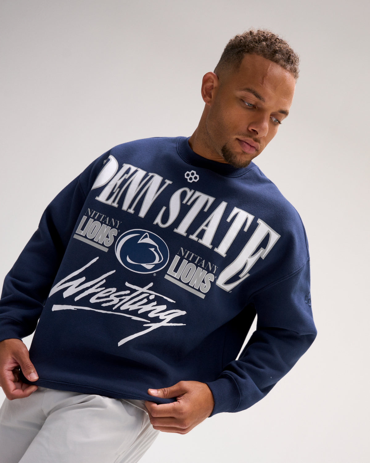Male model wearing the RUDIS Penn State Map Relaxed Comfort Fleece Crewneck in Navy, featuring oversized Penn State lettering, Nittany Lions logos and Wrestling script.