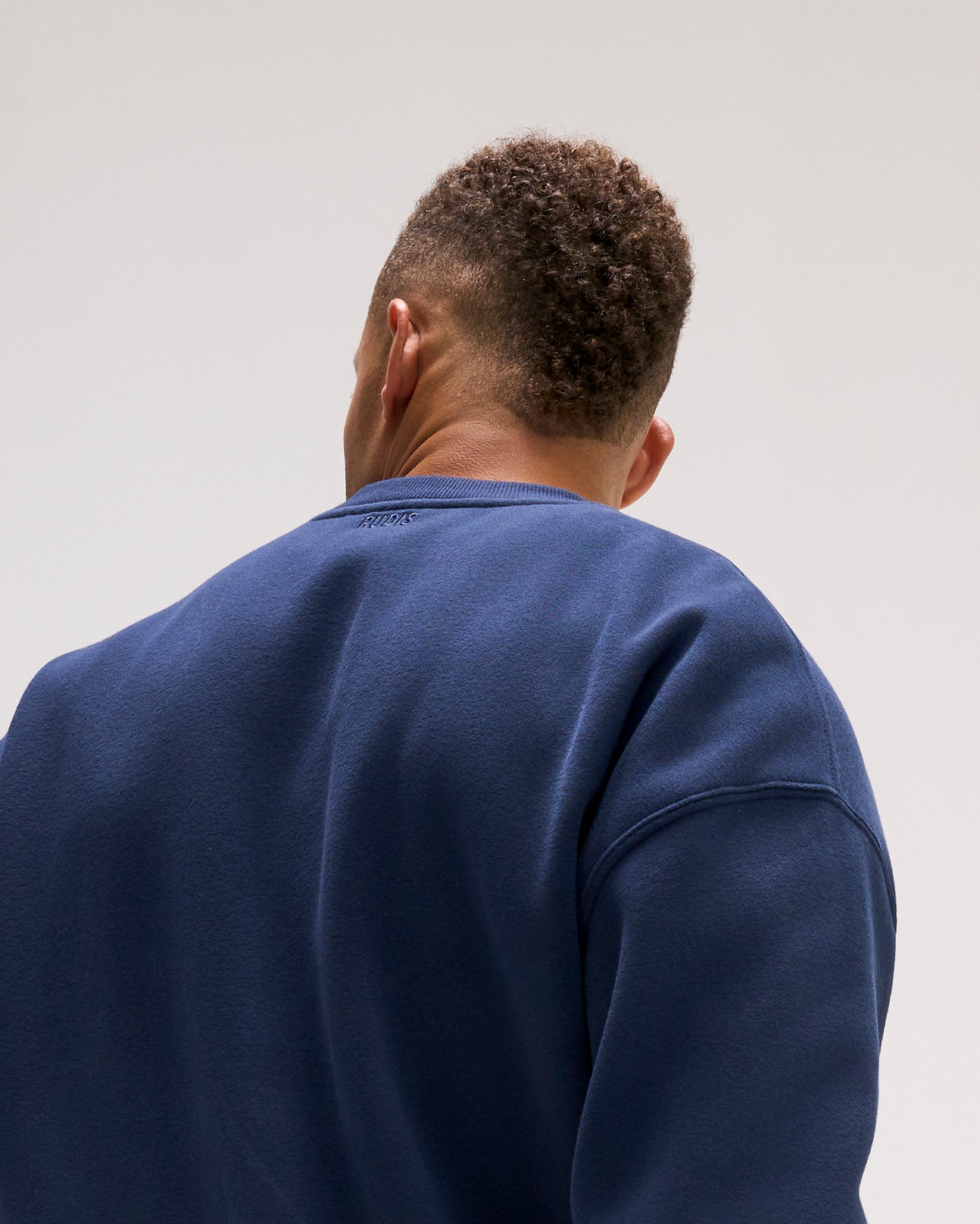 Close-up rear view of the RUDIS Penn State Map Relaxed Comfort Fleece Crewneck in Navy, highlighting the solid navy back, relaxed shoulders and subtle RUDIS neck logo.