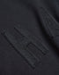 Close-up of a black fabric surface featuring a prominent textured letter H stitched in a contrasting fabric