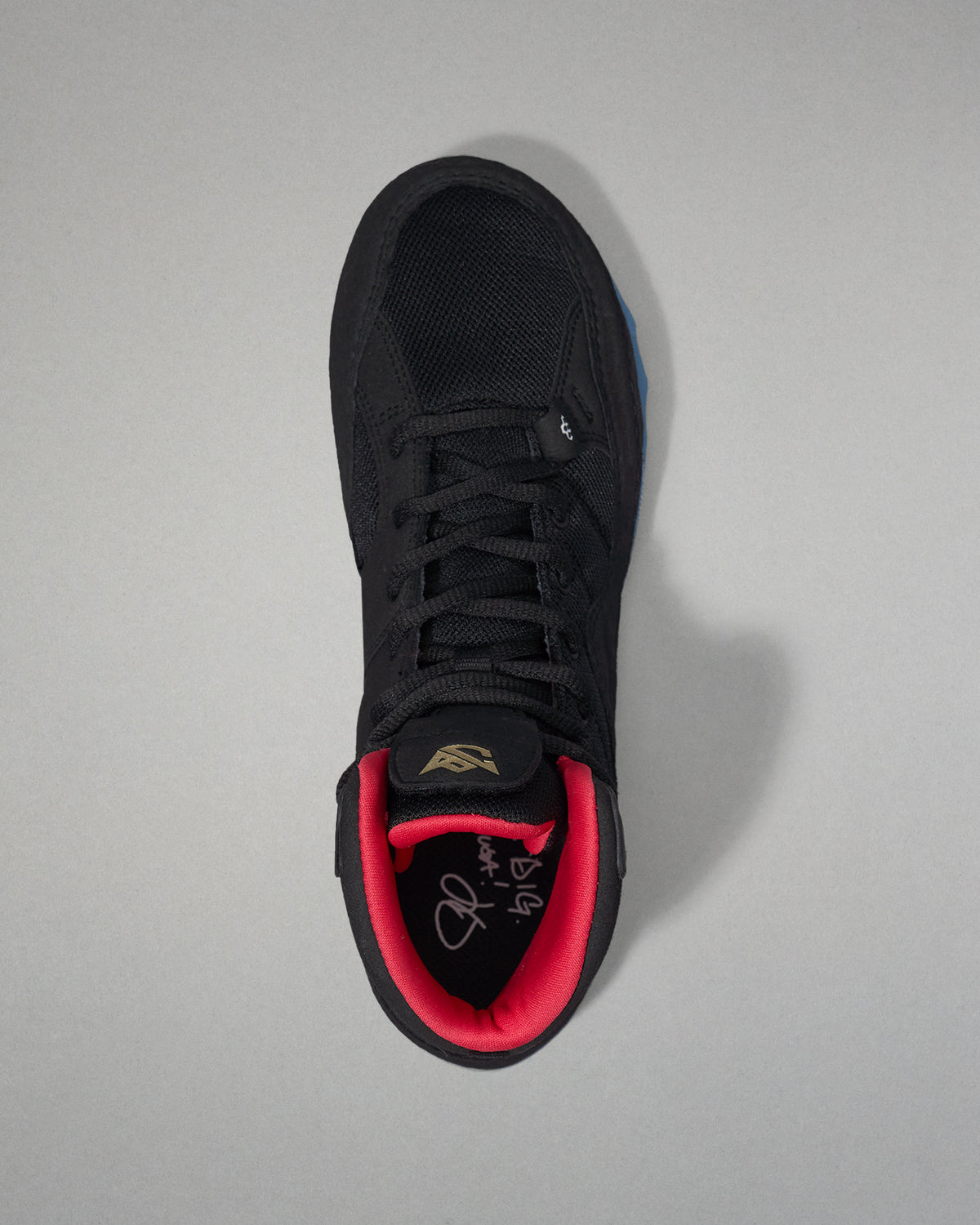 Black wrestling shoe with red lining on a gray background