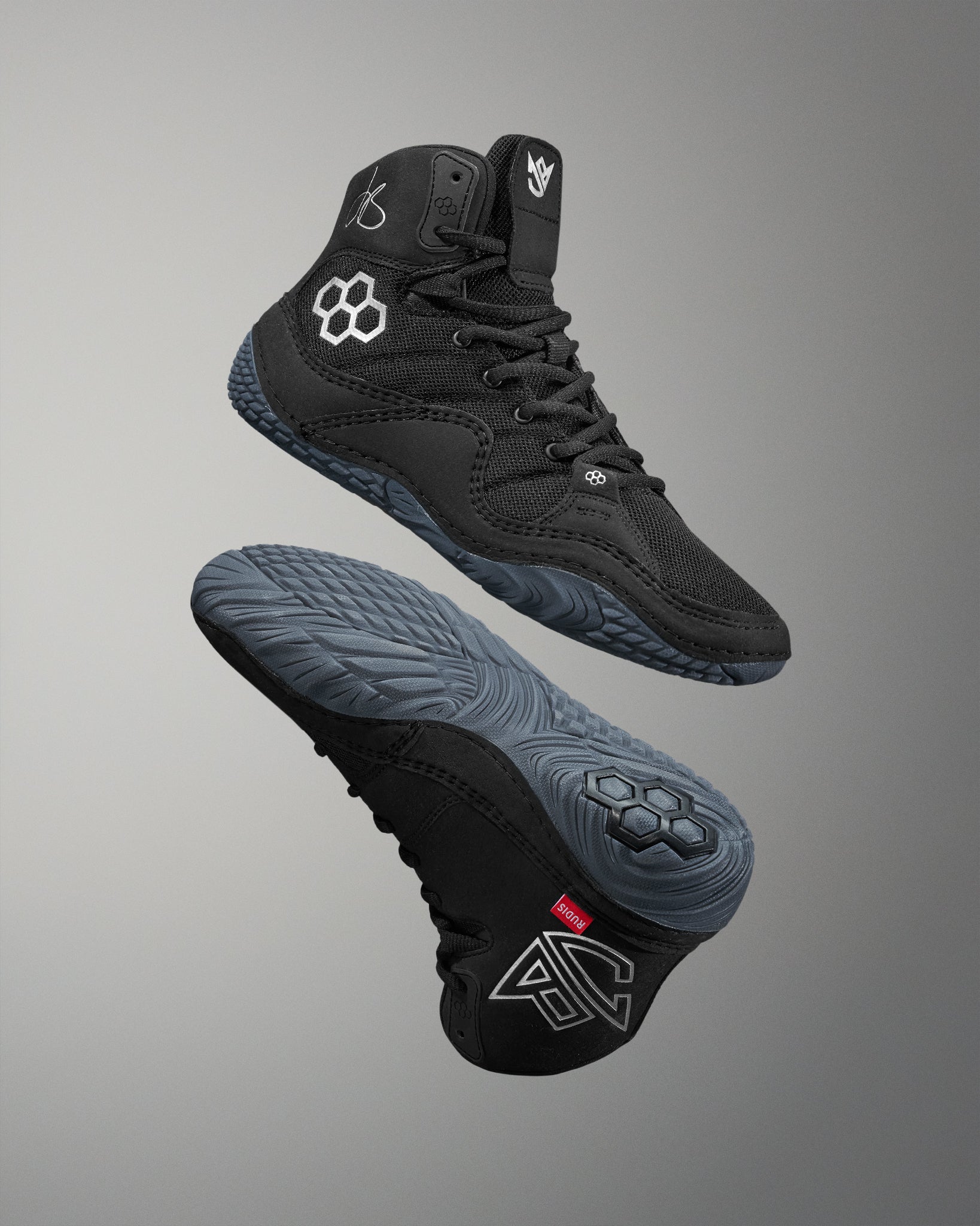 Black Jordan Burroughs wrestling shoes with brand logo on a gray background