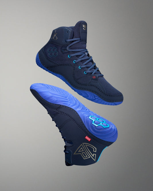 Navy wrestling shoes with blue soles on a gray background