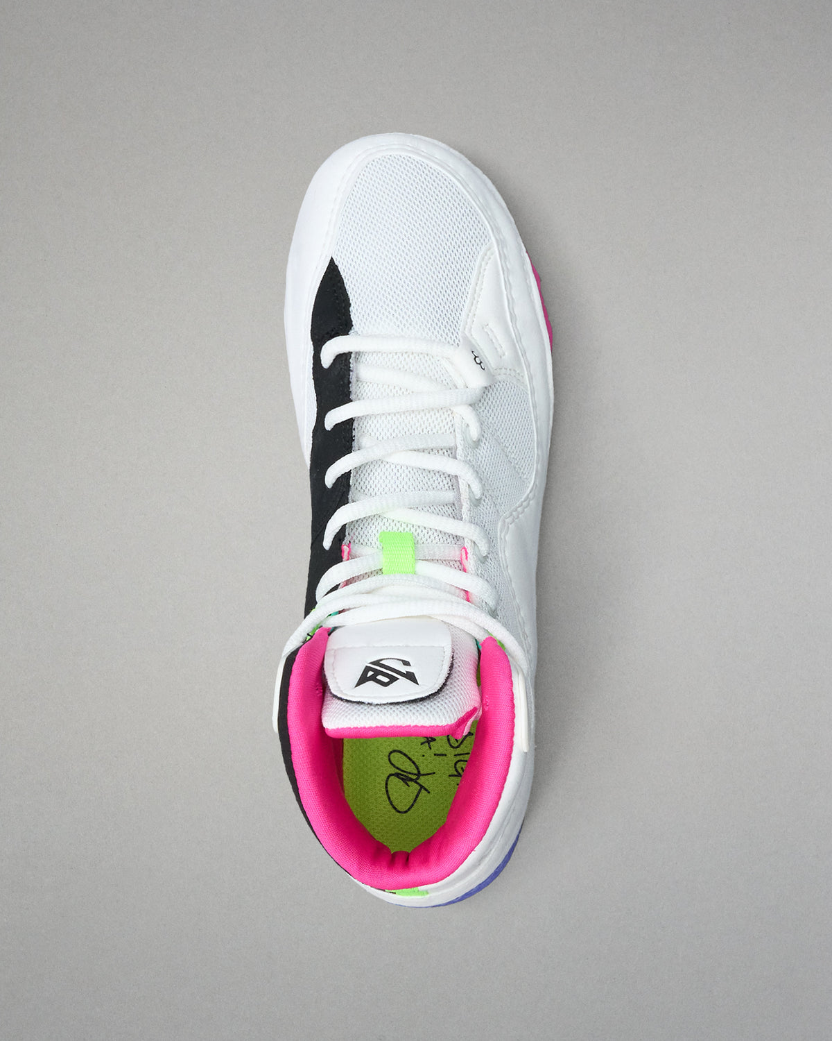 White wrestling shoe with black, pink, and green accents on a gray background