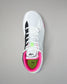 White wrestling shoe with black, pink, and green accents on a gray background