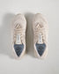 A top view of light beige athletic shoes showcasing a breathable mesh upper featuring a modern design and a prominent logo
