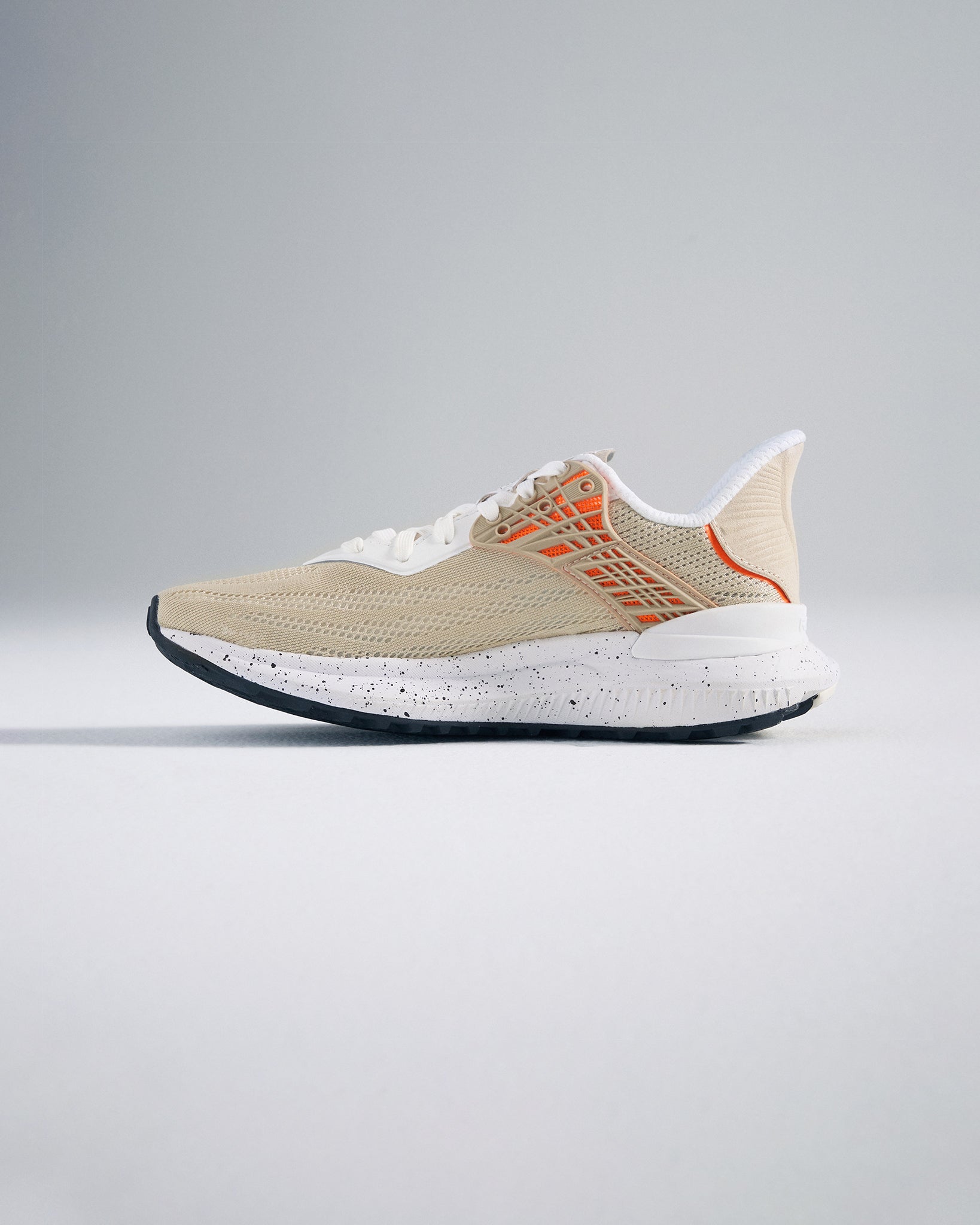 A stylish beige running shoe featuring a breathable mesh upper and a speckled sole designed for both comfort and performance