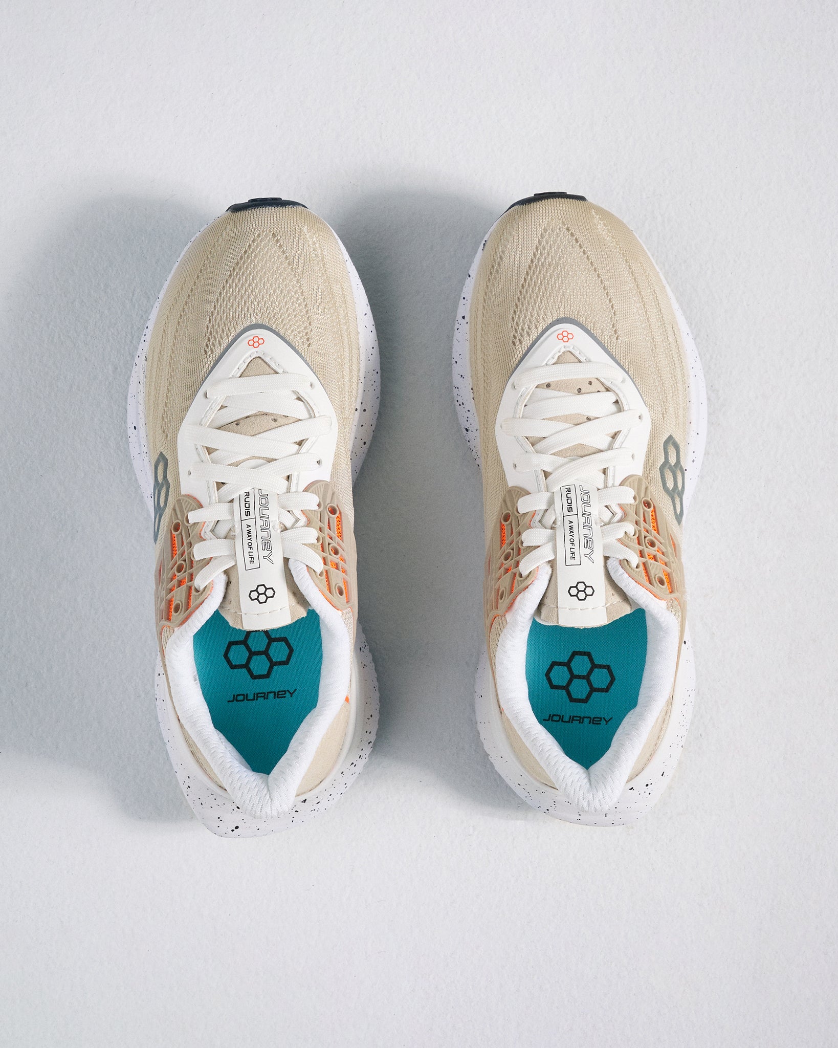 A pair of stylish beige athletic shoes with modern design elements featuring breathable mesh fabric and a vibrant teal insole labeled JOURNEY