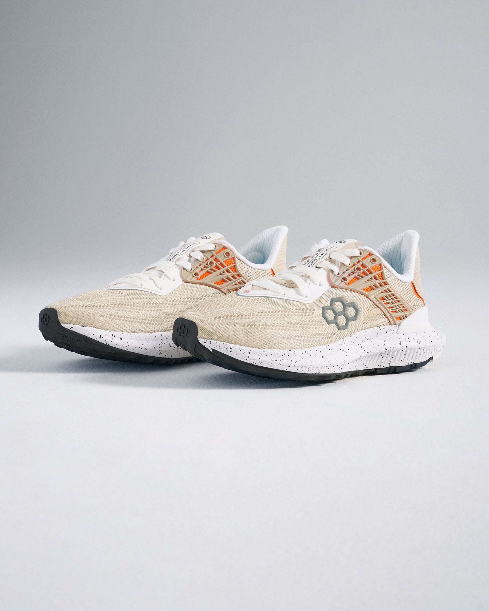 A pair of light beige running shoes featuring an airy mesh upper and contrasting orange details designed for comfort and performance