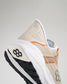 A close-up view of a beige athletic shoe featuring a prominent logo breathable mesh upper and a multi-textured sole designed for performance