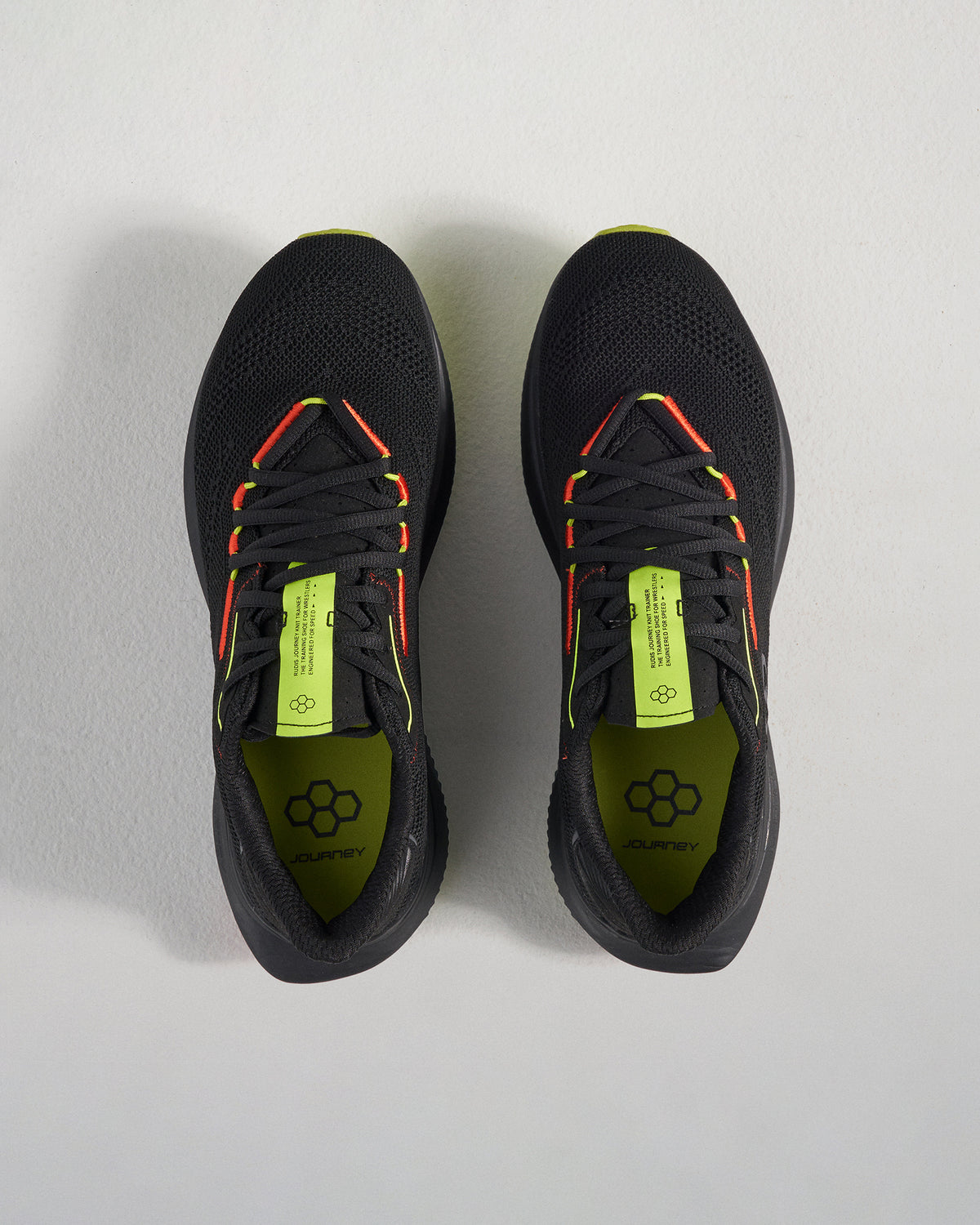 A pair of black athletic shoes with vibrant yellow and red accents showcasing a breathable mesh upper and a modern design