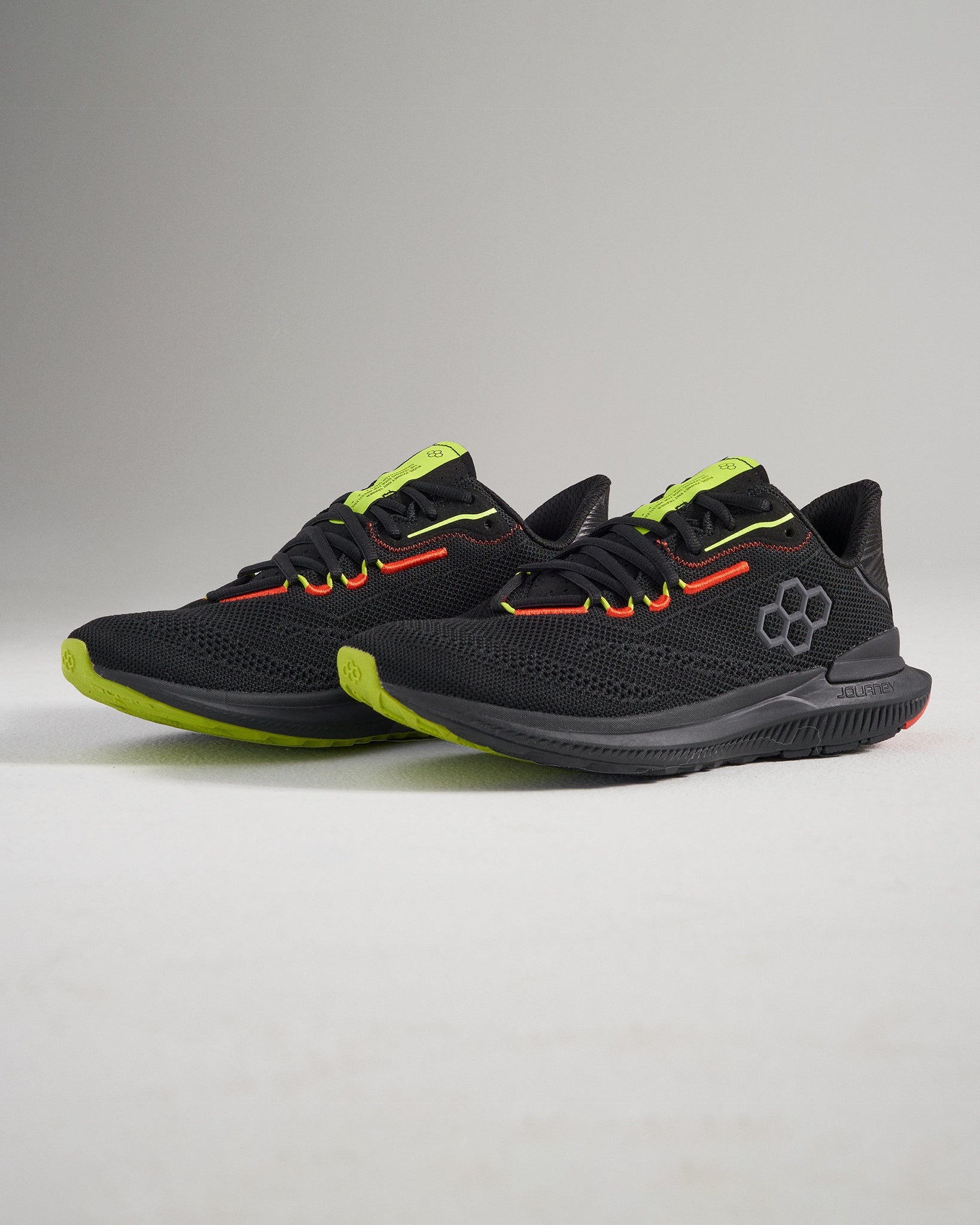 This image displays a stylish pair of black athletic shoes with bright green and red accents designed for performance and comfort