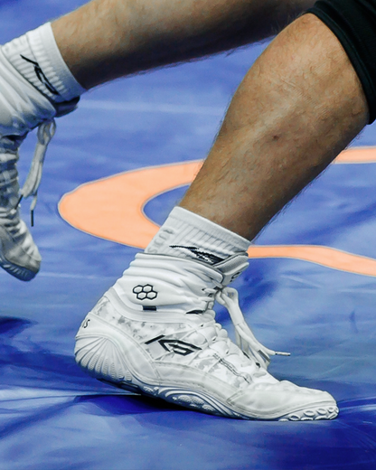 White Wrestling shoes with RUDIS brand logo on a blue sports court